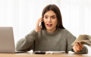Woman holding cash and a phone while feeling stressed about the Chapter 7 bankruptcy process in Michigan.